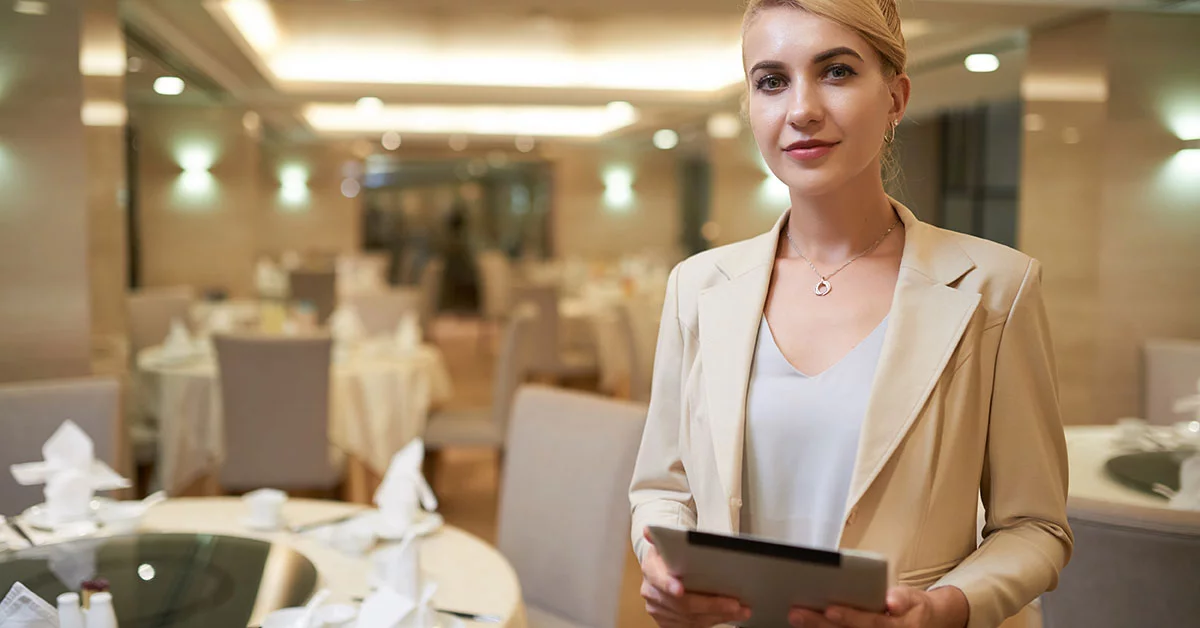 Jolie wedding planner de mariage souriante avec tablette dans un restaurant