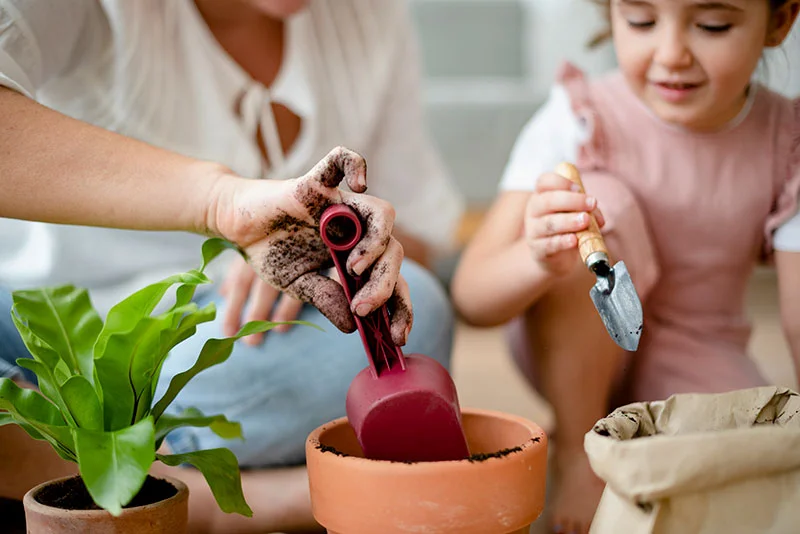 Une petite fille plantes des fleures dans un nouveau pot