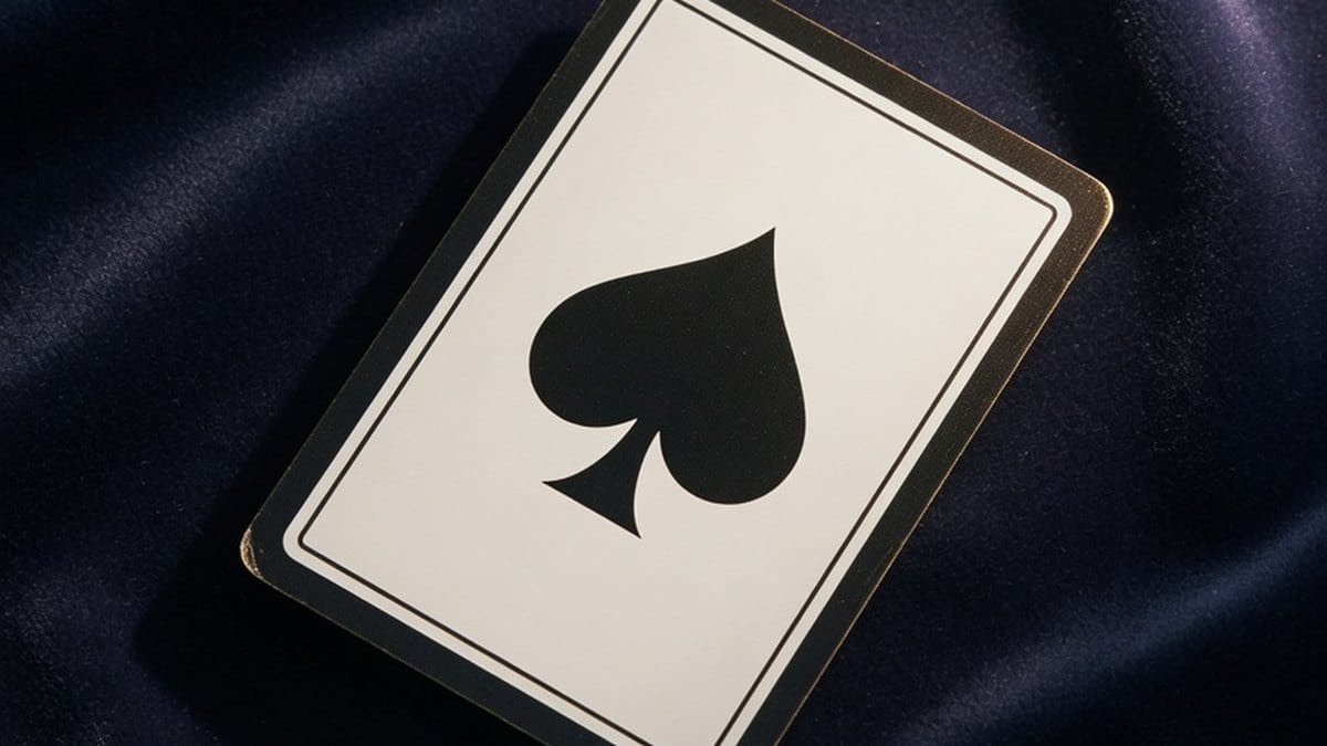 Carte à jouer as de pique posée sur un tissu sombre, ambiance symbolique
