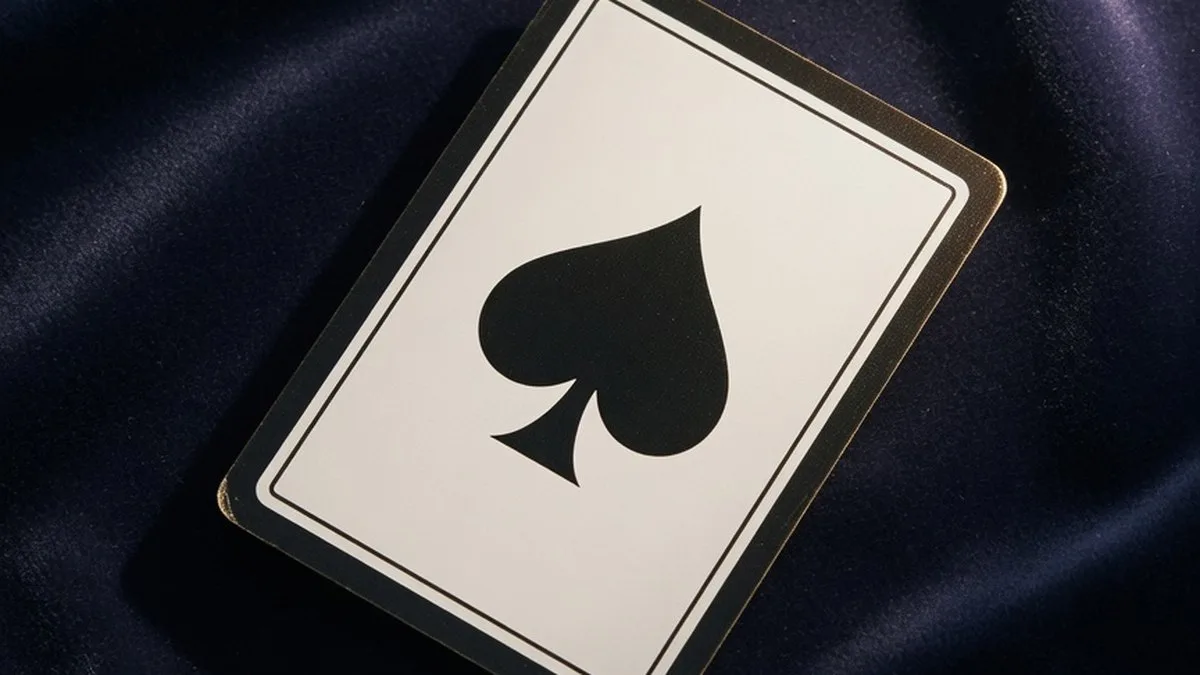 Carte à jouer as de pique posée sur un tissu sombre, ambiance symbolique