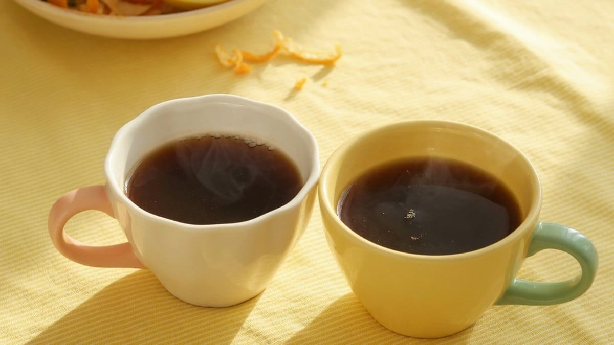 Deux tasses partagées entre amis dans une lumière jaune chaleureuse, symbole d'amitié et de bonne humeur